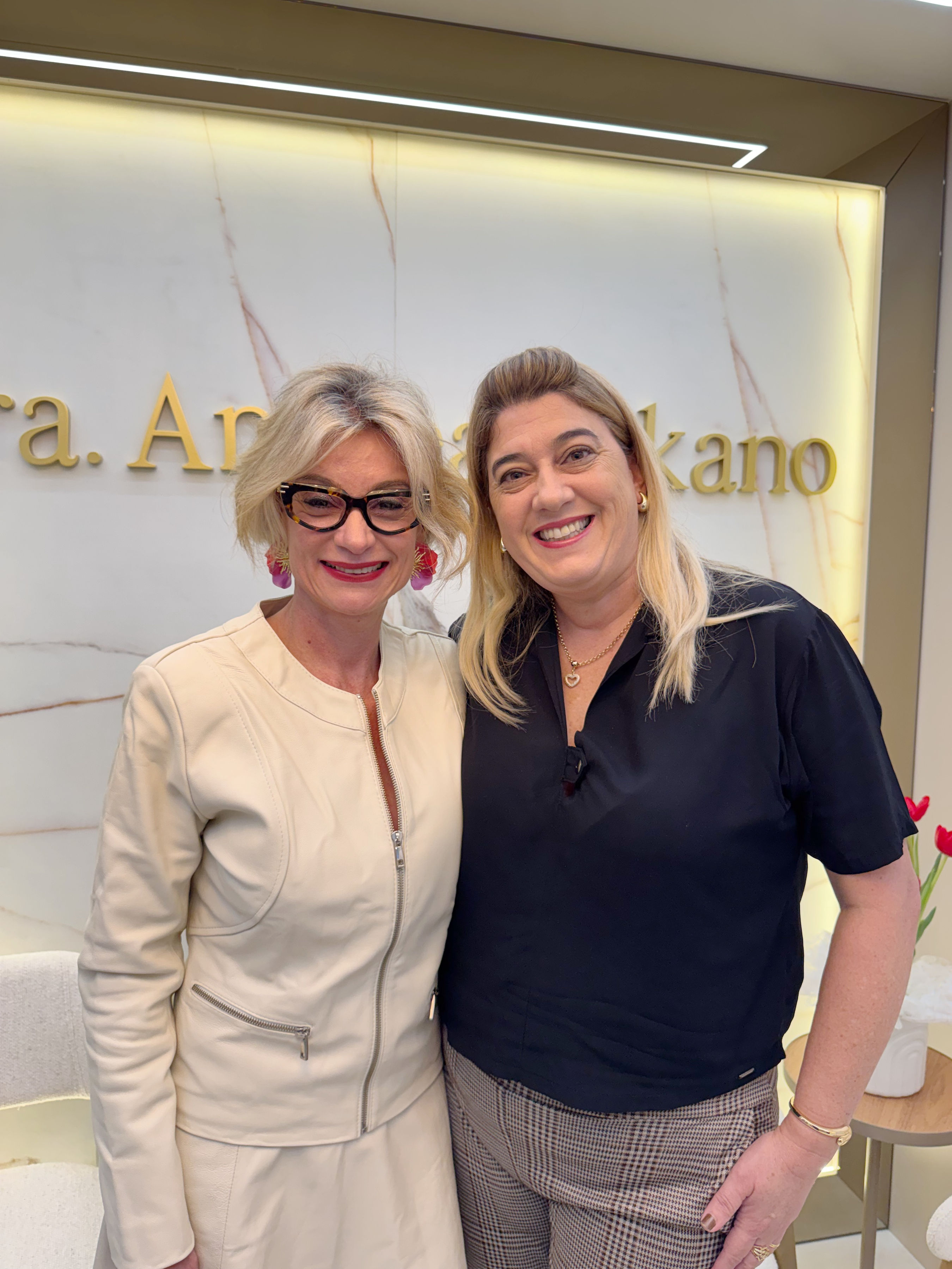 Dra. Andrea Nakano com paciente em frente ao letreiro do consultório